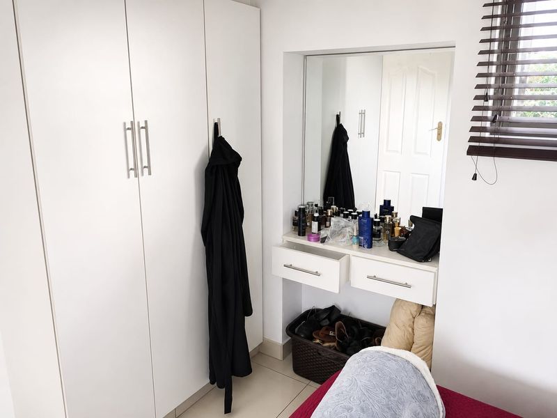 Bedroom featuring white built-in cupboards and a integrated vanity area with a wall-mounted mirror and storage drawers.