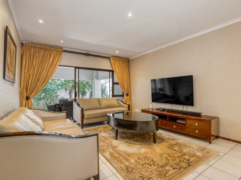 A comfortable living room featuring tiled flooring, recessed lighting, and a large sliding glass door providing access to the outdoor patio area.