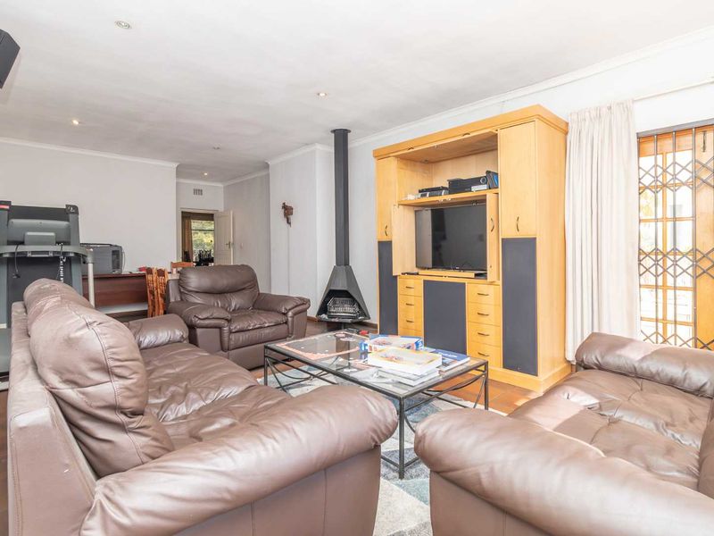 Spacious living room featuring tiled flooring, a modern freestanding fireplace, and direct access to the outdoor area through a secure gate.