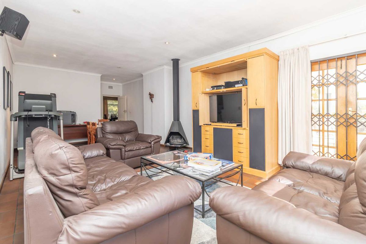 Spacious living room featuring tiled flooring, a modern freestanding fireplace, and direct access to the outdoor area through a secure gate.