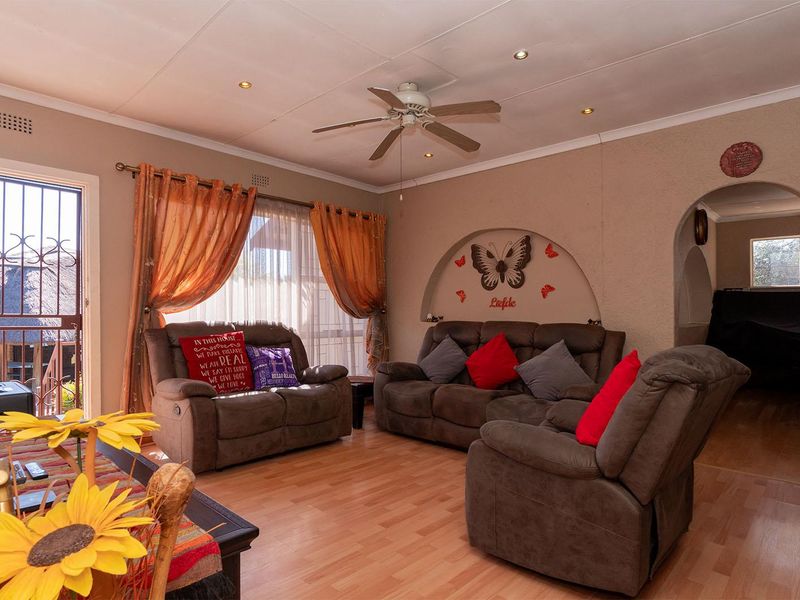 A comfortable living room featuring laminate flooring, a ceiling fan, recessed lighting, and a decorative arched wall niche.