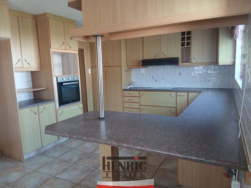 A functional kitchen featuring laminate cabinetry, built-in oven, extractor fan, tiled backsplash, and a breakfast bar with laminate countertops.