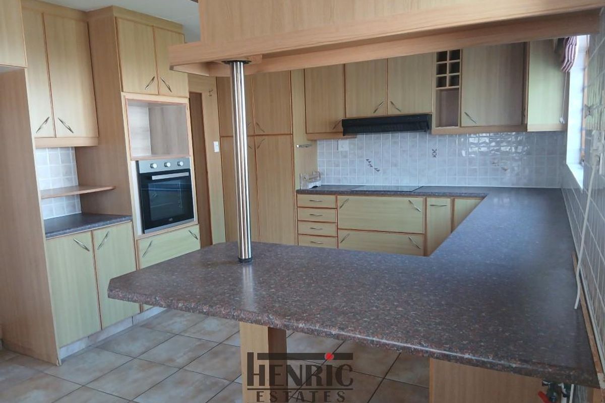A functional kitchen featuring laminate cabinetry, built-in oven, extractor fan, tiled backsplash, and a breakfast bar with laminate countertops.