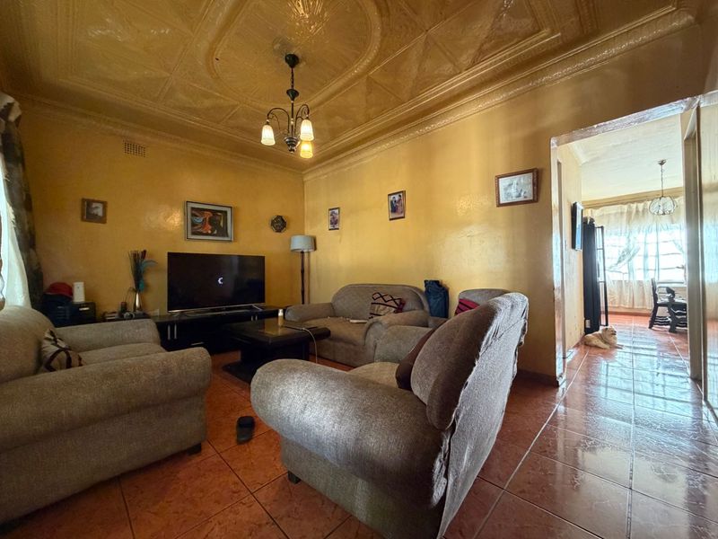 A living room featuring tiled flooring and a decorative pressed metal ceiling, offering a dated aesthetic with potential for modernization.
