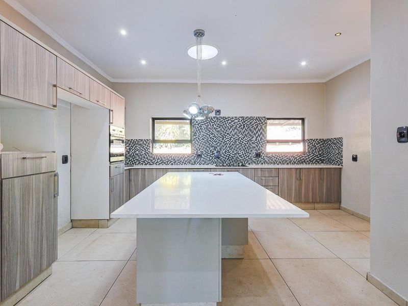 Modern kitchen featuring a large central island, extensive built-in cabinetry, mosaic tile backsplash, and tiled flooring with recessed lighting.