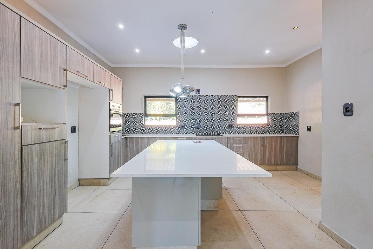 Modern kitchen featuring a large central island, extensive built-in cabinetry, mosaic tile backsplash, and tiled flooring with recessed lighting.