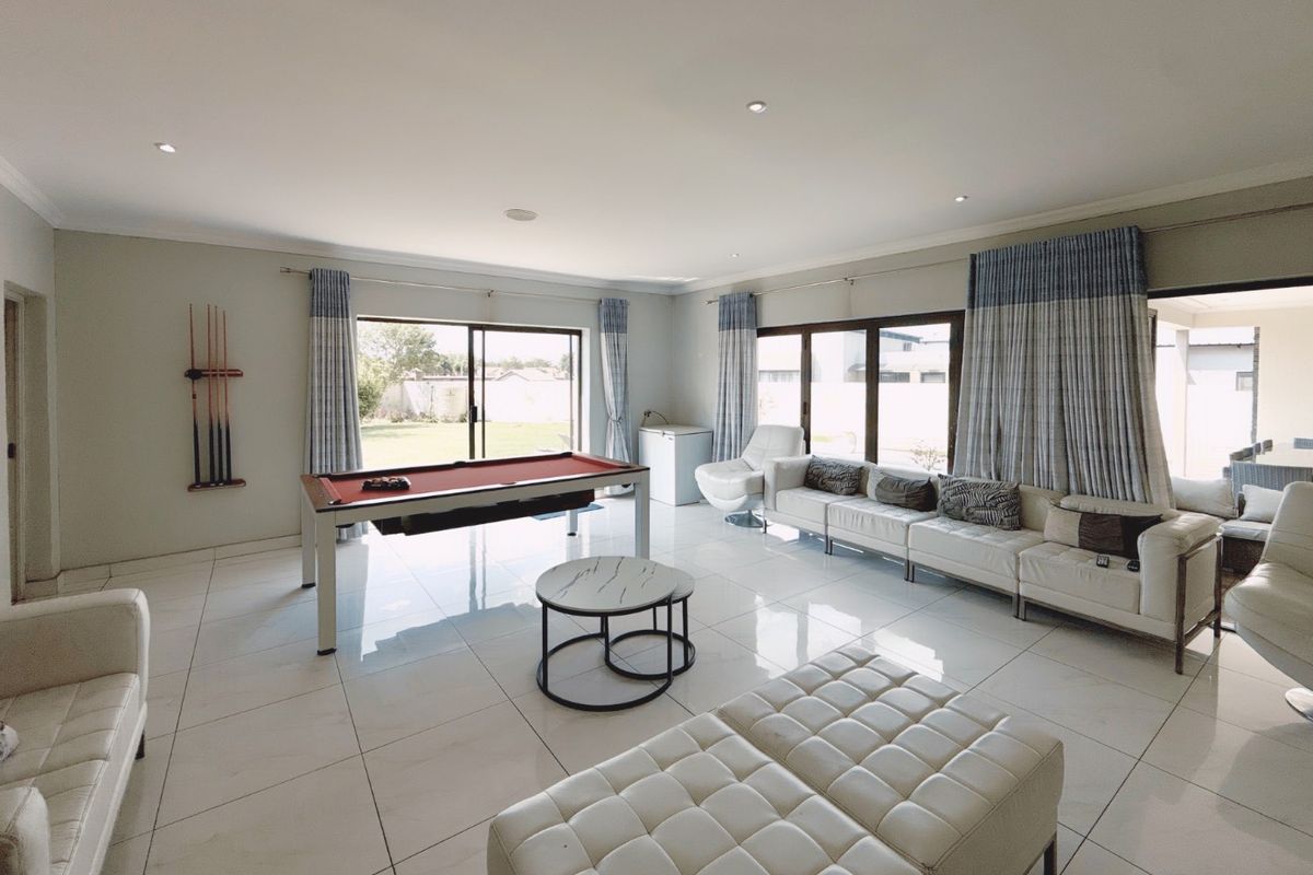 Spacious living area featuring large format floor tiles, recessed downlighting, and multiple sliding glass doors providing ample natural light and access to the garden.