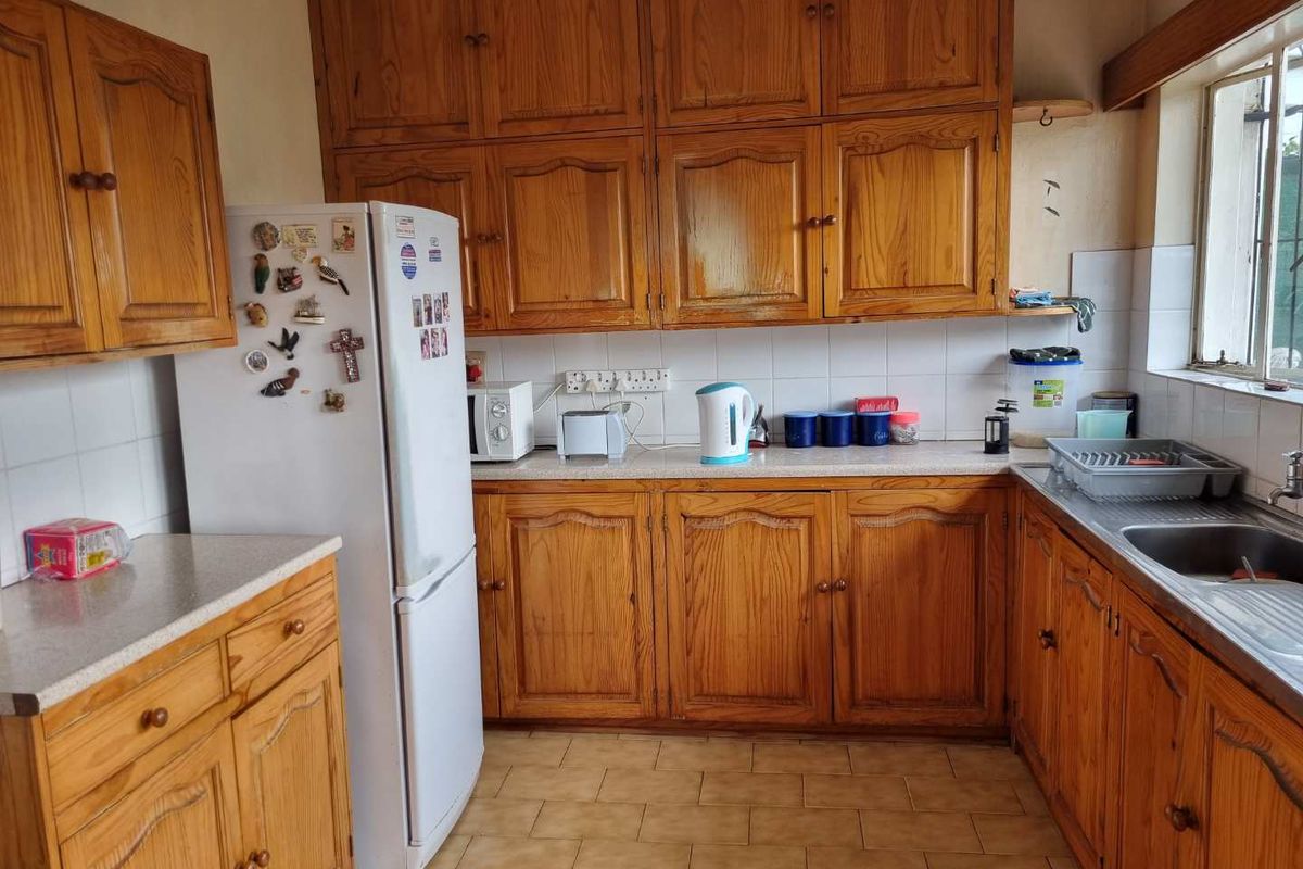 A functional kitchen featuring traditional wooden cabinetry, laminate countertops, a stainless steel sink, and tiled flooring, offering a classic layout with ample storage space.