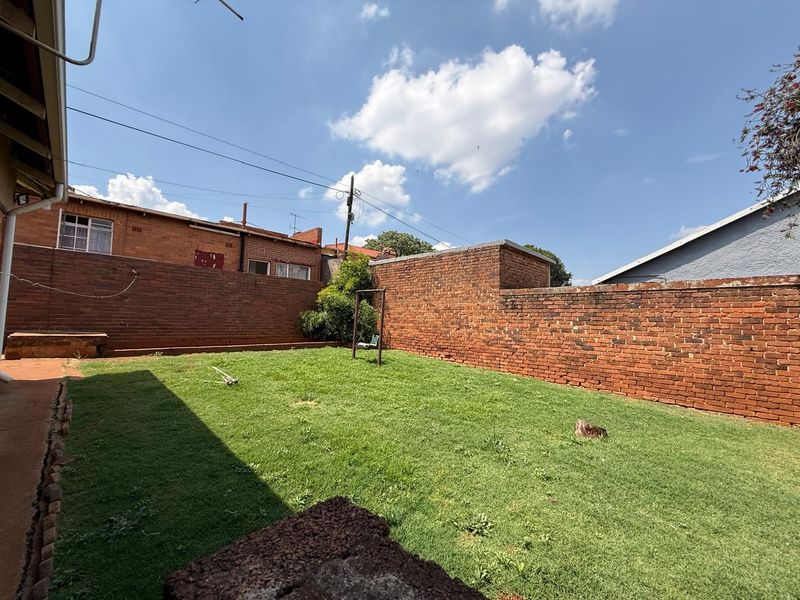 A private rear garden featuring a level lawn area enclosed by traditional red brick boundary walls.