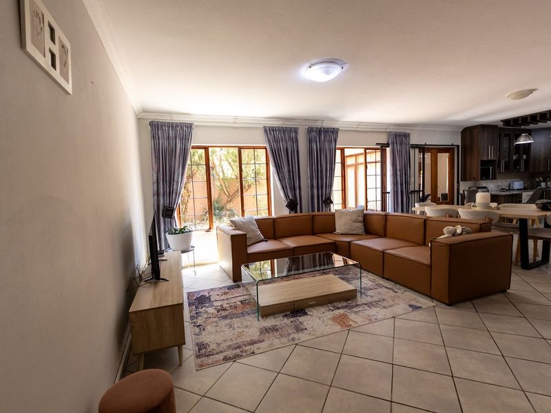 Spacious open-plan living and dining area featuring tiled floors, abundant natural light through sliding glass doors, and a modern integrated kitchen.