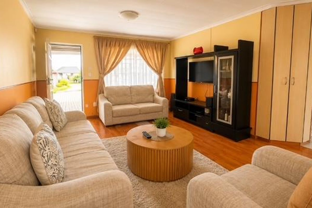 A comfortable living room featuring laminate flooring, built-in cabinetry, and direct access to the exterior through a glass-panelled door.