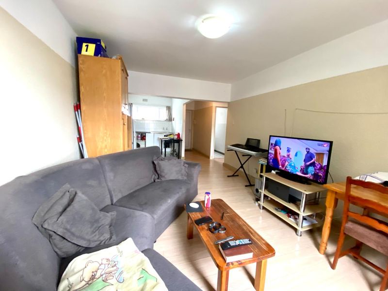 Open plan living area featuring laminate flooring and neutral wall tones, providing a functional space with direct access to the kitchen area.
