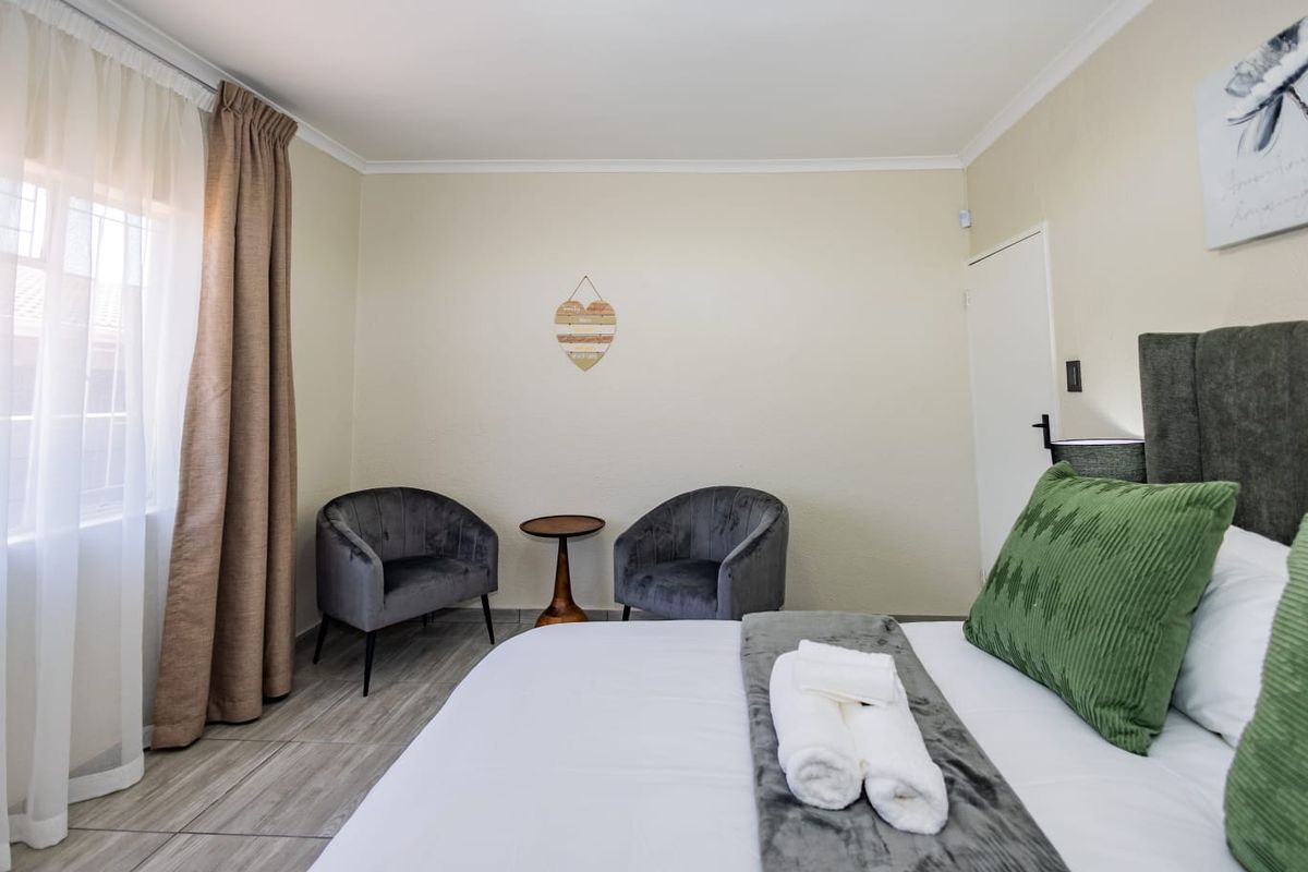 A well-maintained bedroom featuring neutral wall tones, tiled flooring, and a window with curtain treatments.