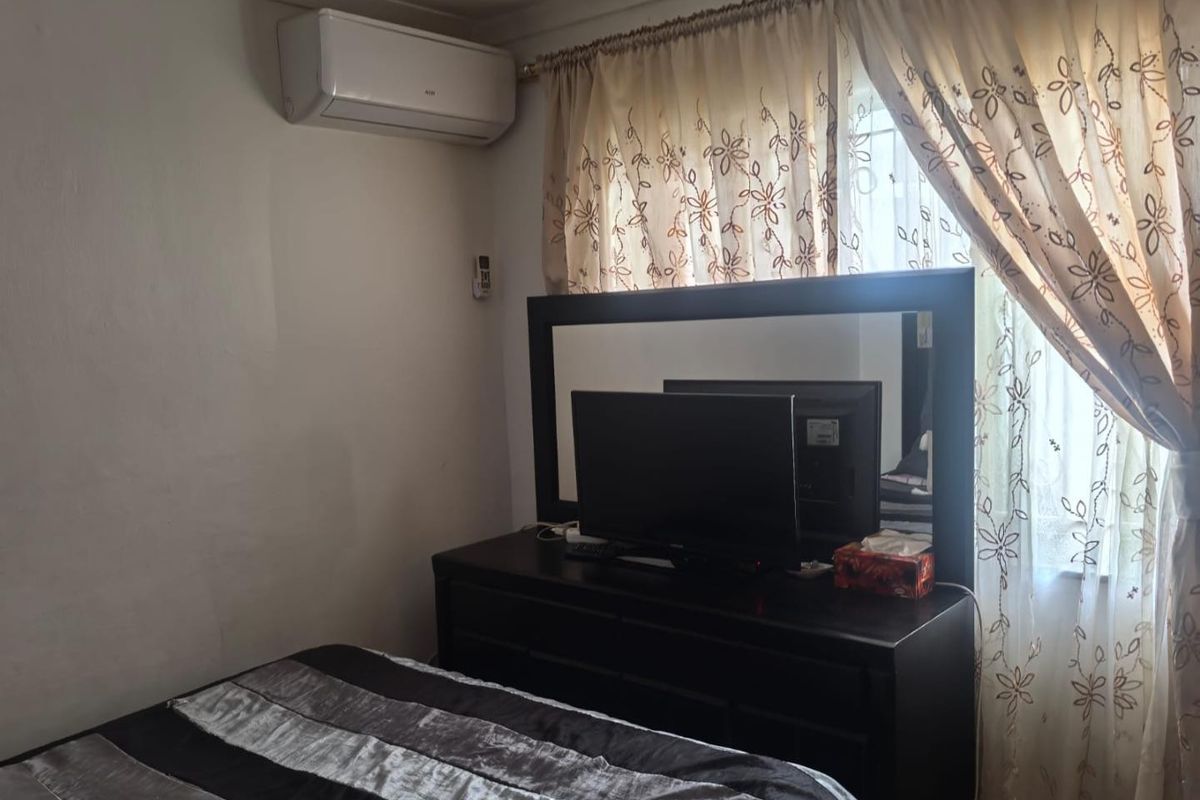 A functional bedroom featuring a wall-mounted split-system air conditioner and window treatments.