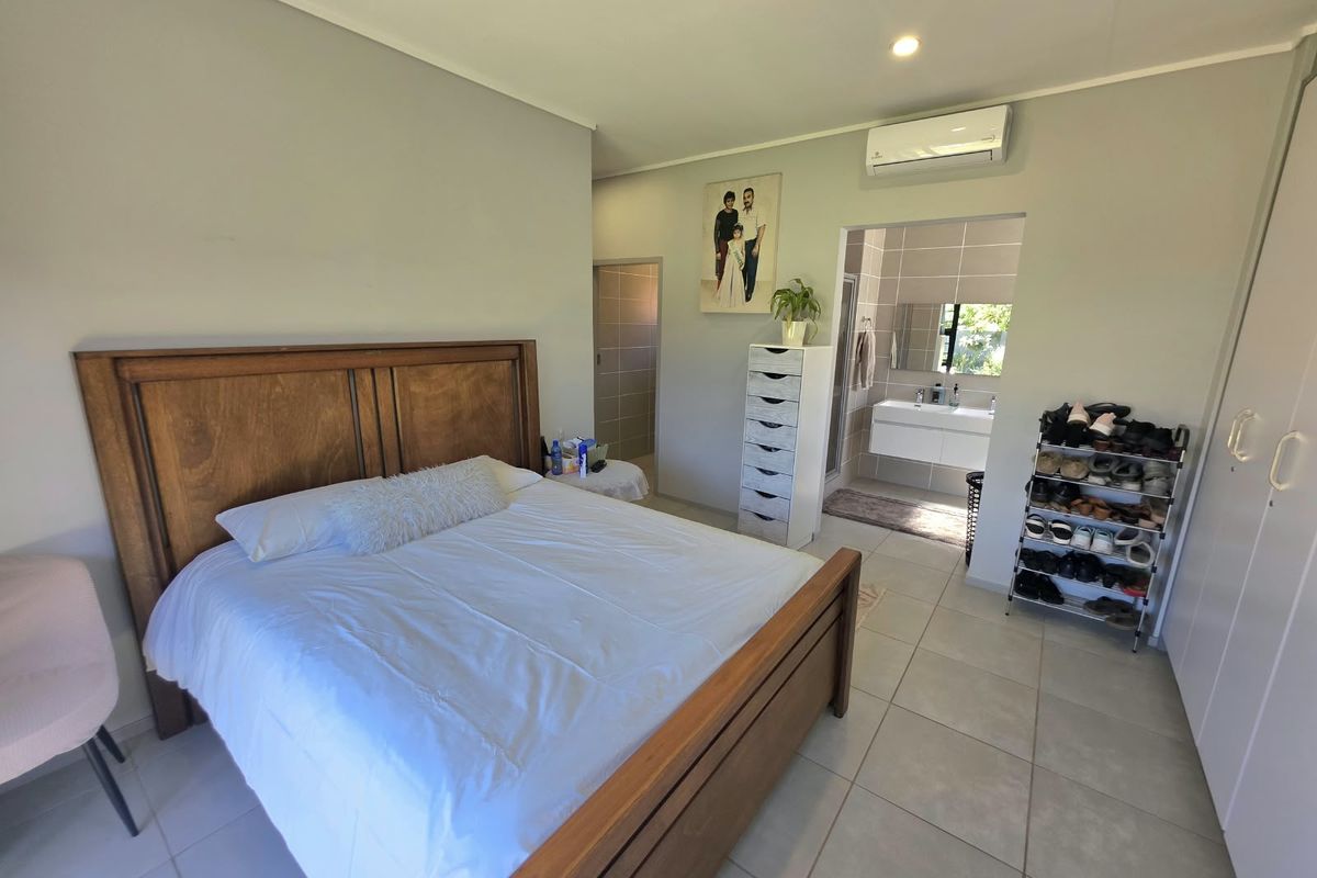 Spacious bedroom featuring tiled flooring, built-in cupboards, an air conditioning unit, and direct access to an en-suite bathroom.