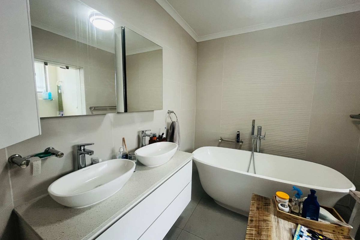 Modern bathroom featuring a double vanity with vessel sinks, a freestanding bathtub, and contemporary wall-mounted fixtures.