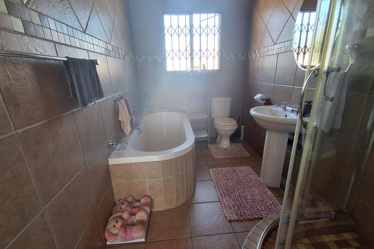 A functional bathroom featuring a built-in bathtub, pedestal sink, toilet, and a separate shower enclosure with full-height wall tiling.