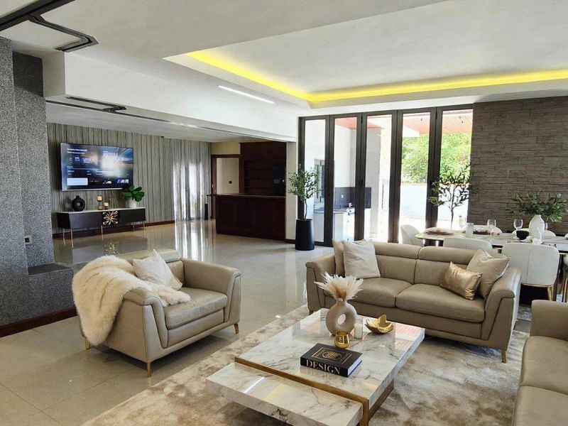 Spacious open-plan living and dining area featuring modern recessed lighting, a striking stone feature wall, and large bi-fold doors leading to the outdoors.
