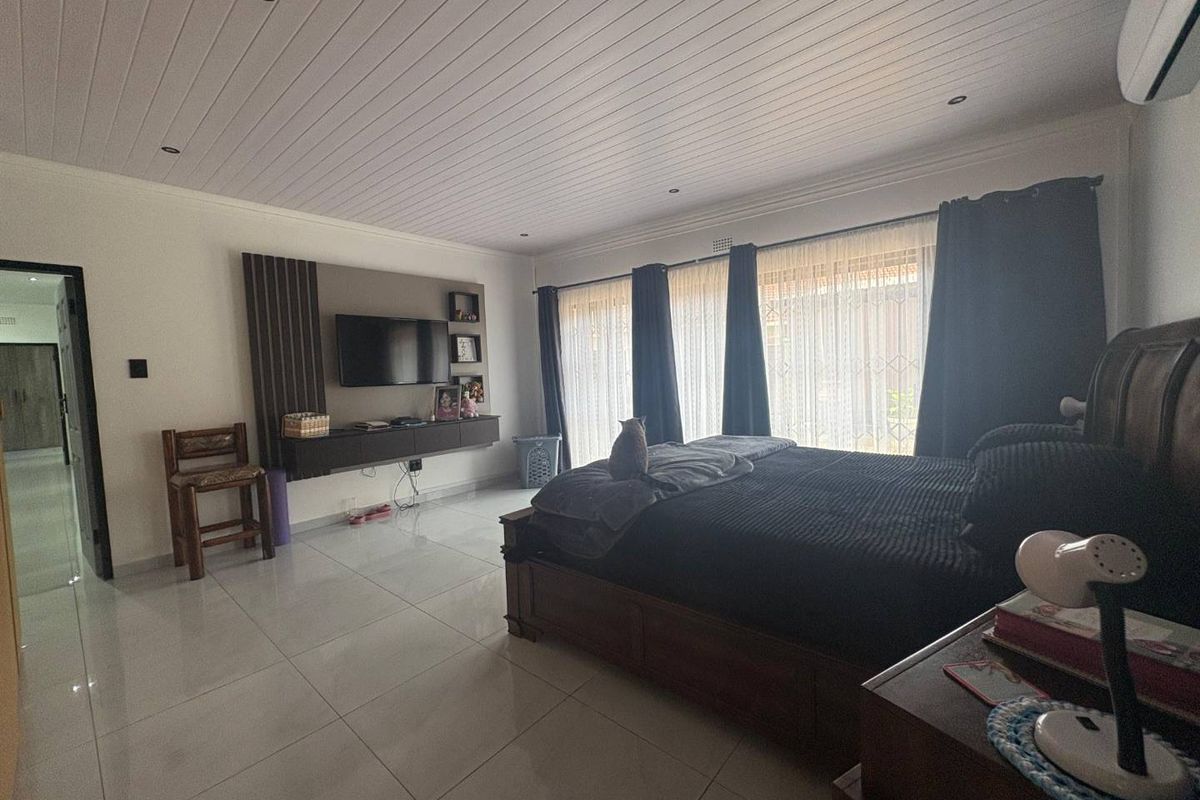 Spacious bedroom featuring tiled flooring, a tongue and groove ceiling with recessed lighting, a built-in media console, and sliding glass doors leading outdoors.
