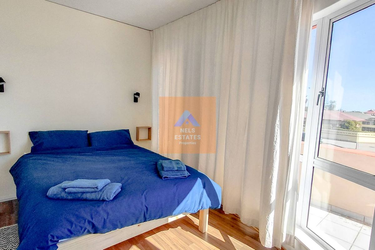 A bright bedroom featuring laminate flooring and a large sliding glass door providing access to an outdoor area.