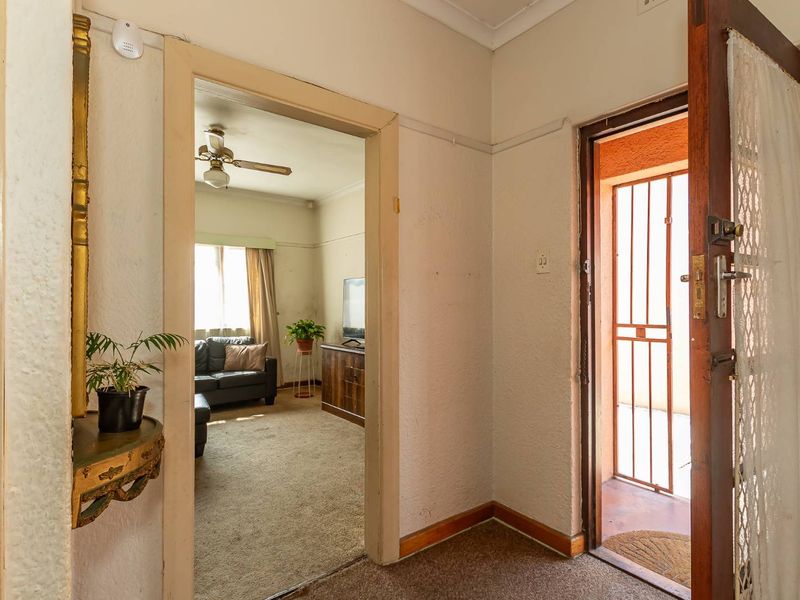 Entrance hallway leading into a living area, featuring carpeted flooring and a security gate at the main entrance.
