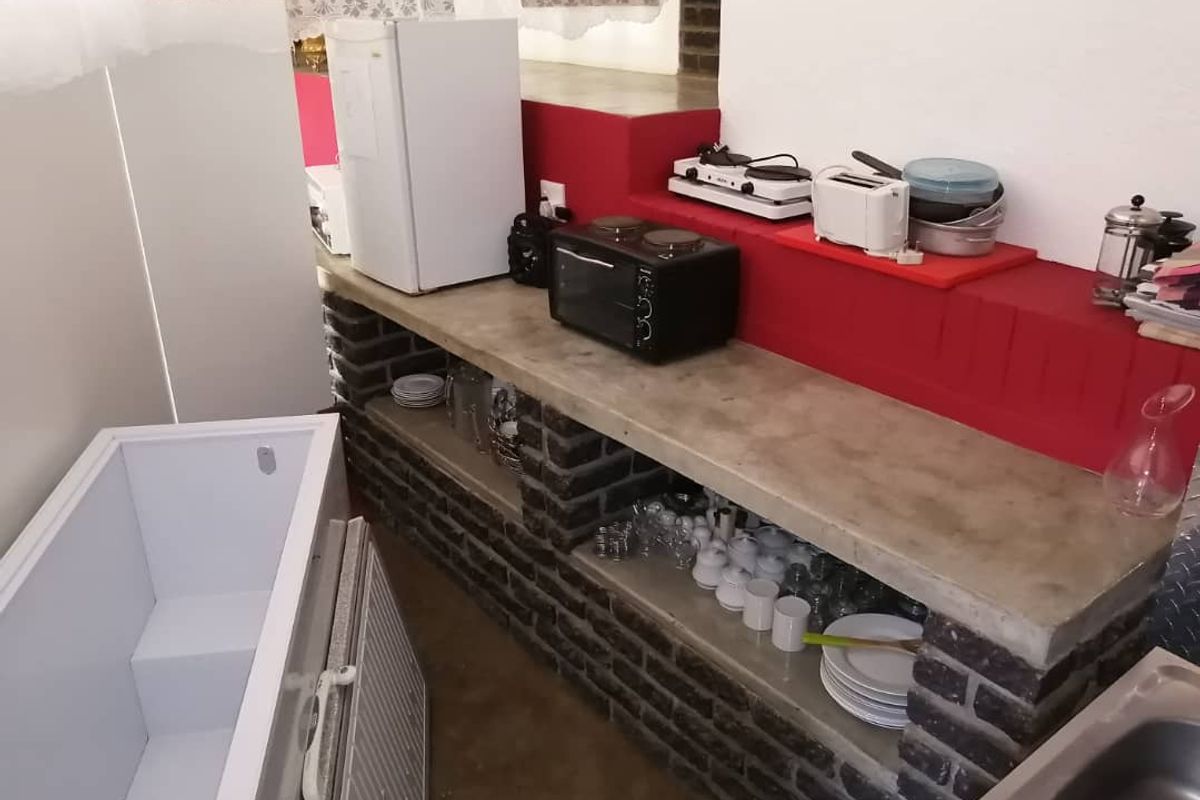 A functional kitchenette area featuring a concrete countertop, exposed brick base cabinetry, and a stainless steel sink.