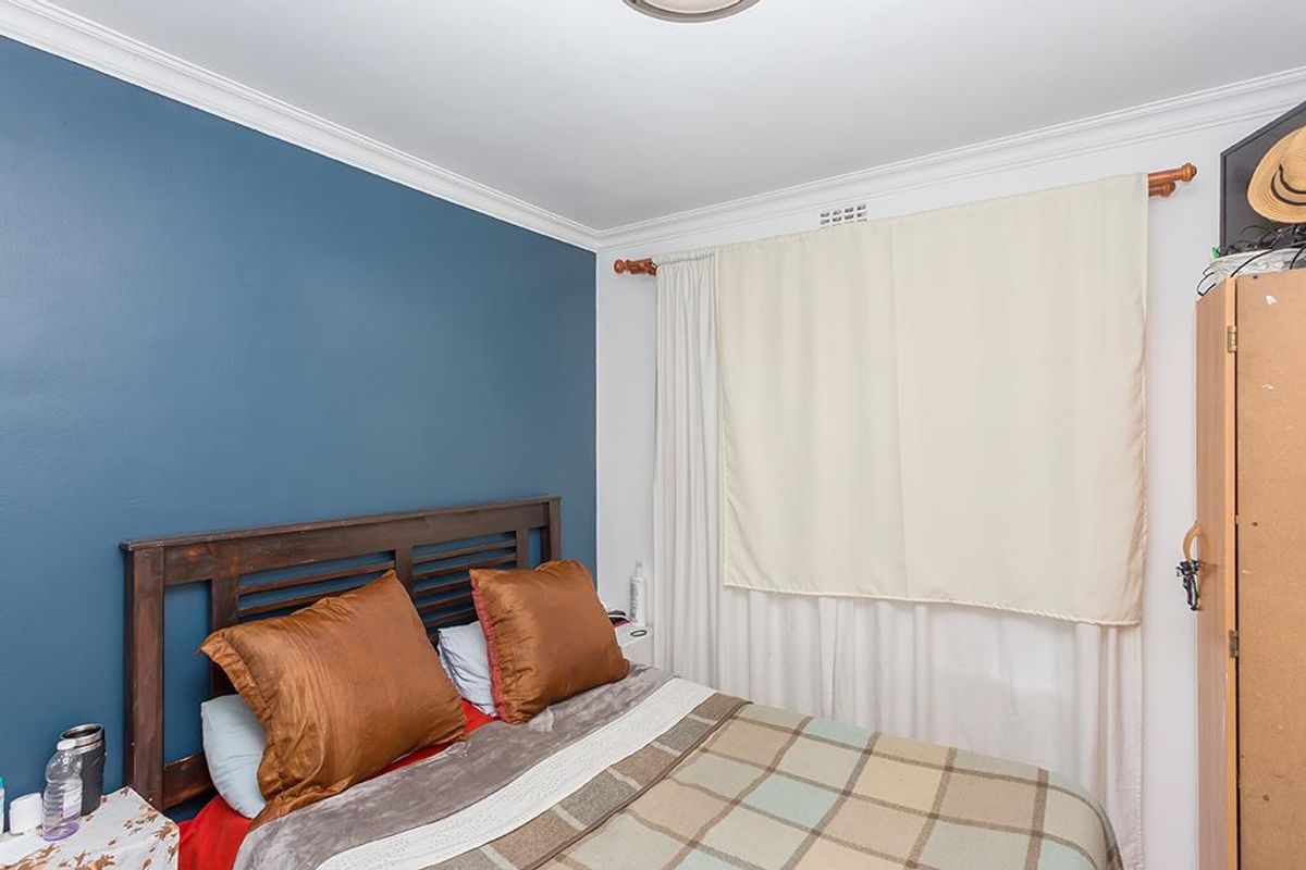 A bedroom featuring a blue accent wall, crown molding, and a window with curtain tracks.