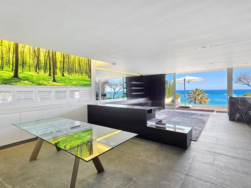 Spacious open-plan living area featuring modern built-in cabinetry, stone flooring, and expansive sliding glass doors opening to a scenic ocean view.