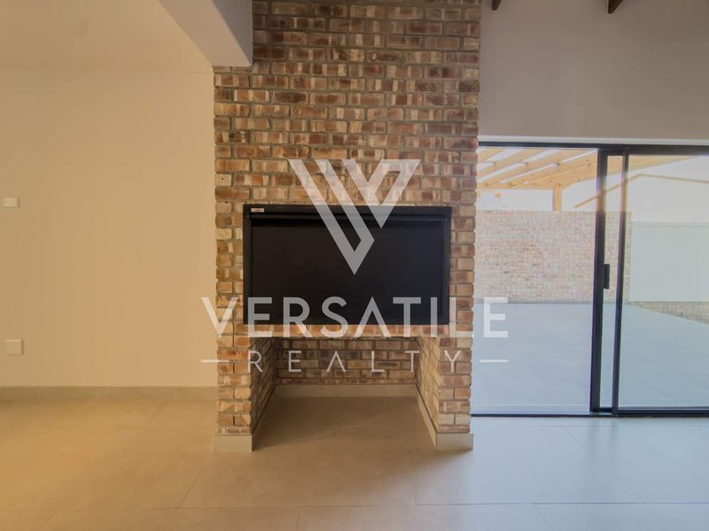 Spacious living area featuring a prominent exposed brick fireplace and large sliding glass doors leading to an outdoor patio space.