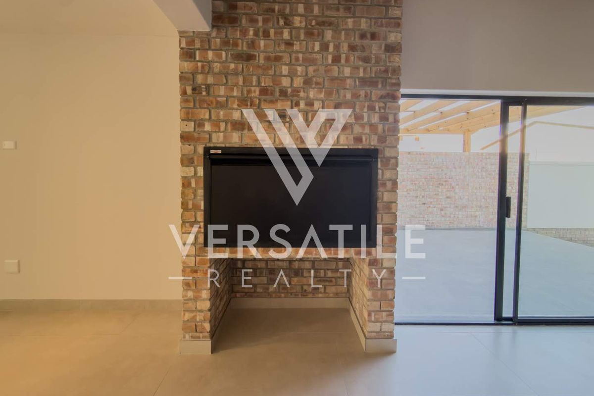 Spacious living area featuring a prominent exposed brick fireplace and large sliding glass doors leading to an outdoor patio space.