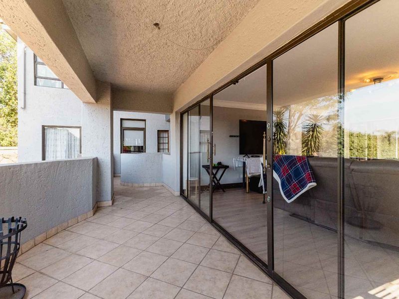 A covered balcony featuring tiled flooring and large sliding glass doors, providing a seamless transition to the interior living space.