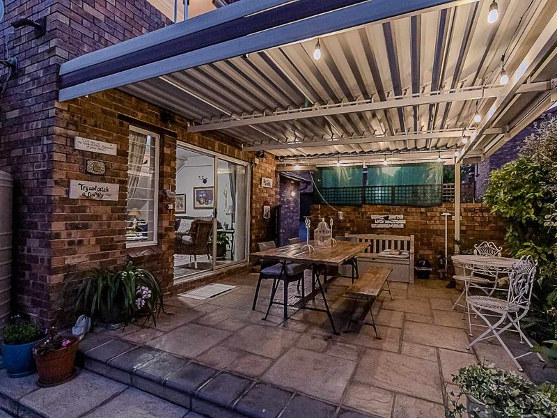 A covered outdoor patio area featuring brick walls, paved flooring, and direct access to the interior living space through sliding glass doors.