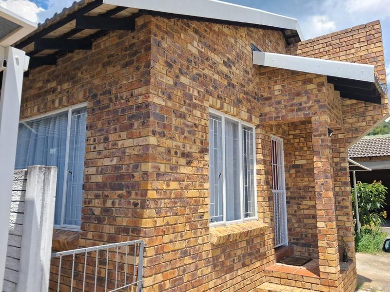 A well-maintained face brick exterior facade featuring secure window bars and a covered entrance area.