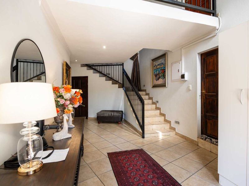 A spacious entrance hall featuring tiled flooring, a staircase with a wrought iron balustrade, and built-in storage cabinetry.