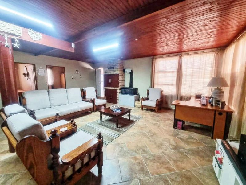 Spacious living room featuring a rustic exposed timber ceiling, tiled flooring, and a traditional built-in brick fireplace with a wood-burning stove.