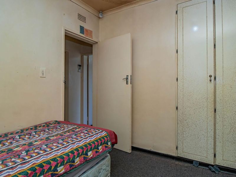 A bedroom featuring built-in cupboards and carpeted flooring, requiring cosmetic updates to improve the overall condition and aesthetic appeal.