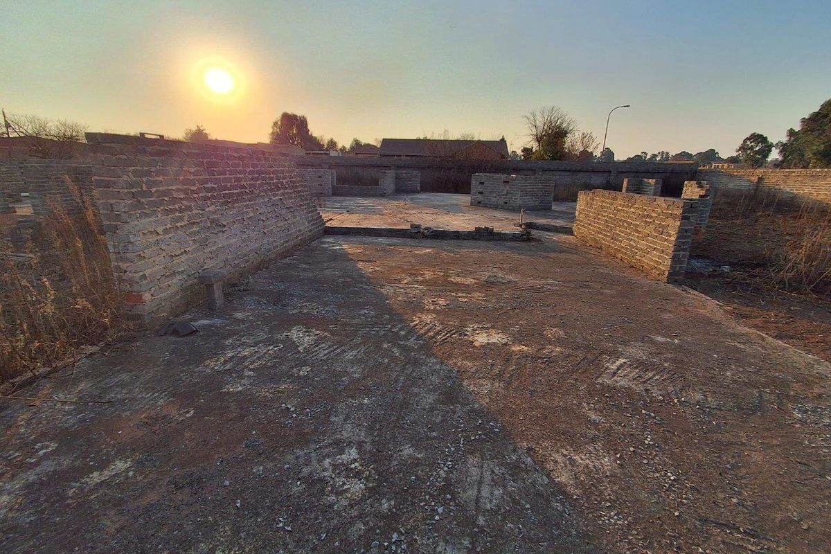 A vacant residential plot featuring an unfinished concrete slab foundation and partial brick perimeter walls, ideal for new development.