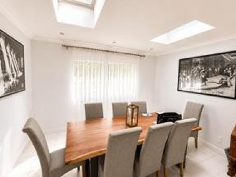 A bright dining room featuring tiled flooring, recessed lighting, and two skylights that provide ample natural light.