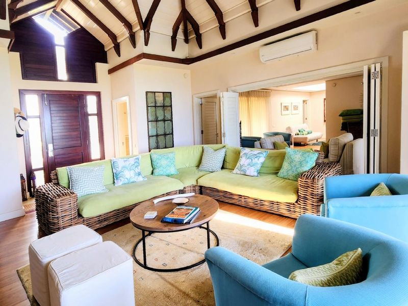 Spacious living room featuring a high vaulted ceiling with exposed timber beams, hardwood flooring, and seamless access to adjacent living areas via bi-fold doors.