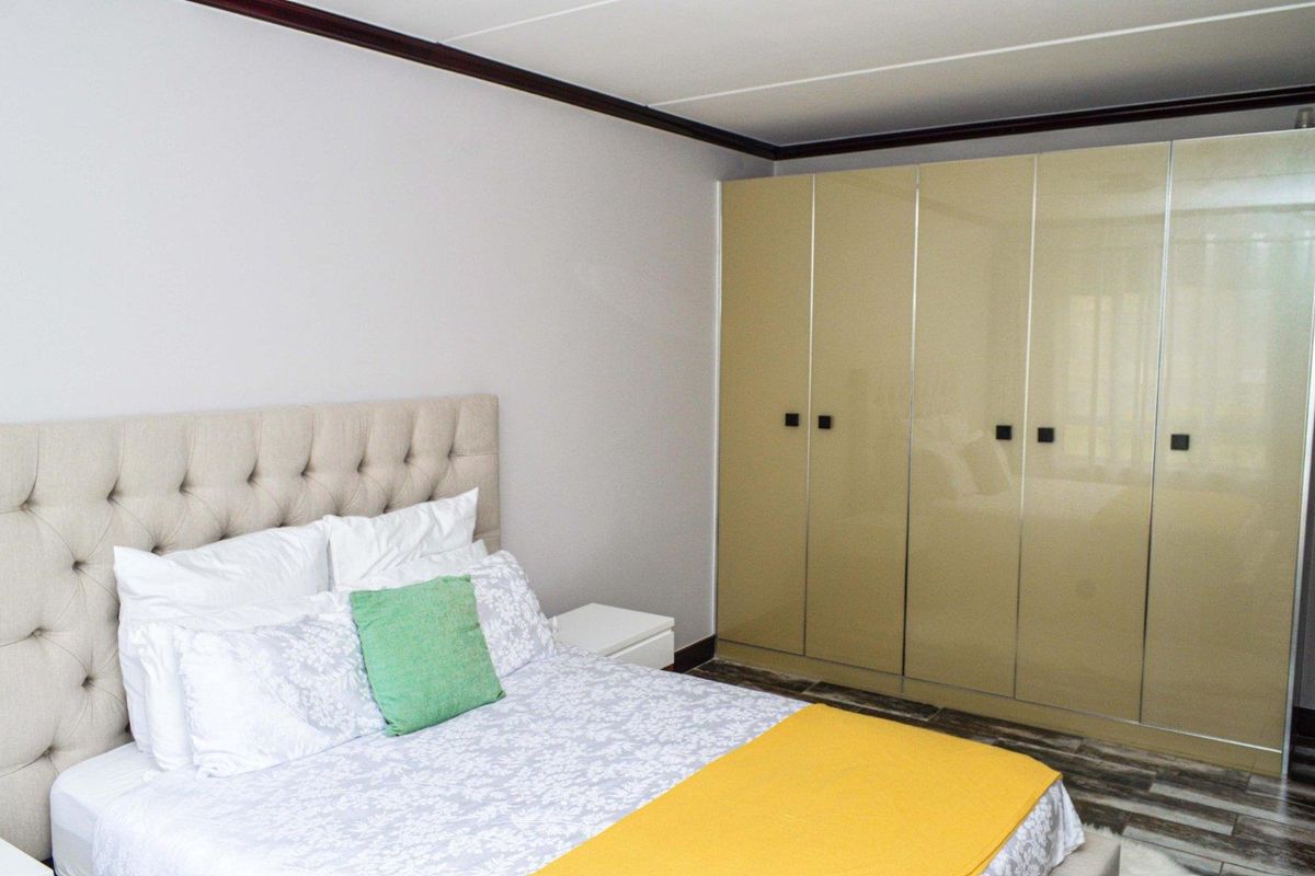 A well-maintained bedroom featuring neutral walls, tiled flooring, and ample built-in cupboard storage.