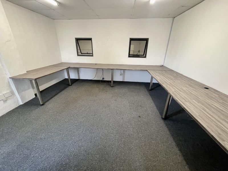 A functional office space featuring built-in desk workstations, carpeted flooring, and overhead lighting, suitable for a professional industrial or commercial environment.