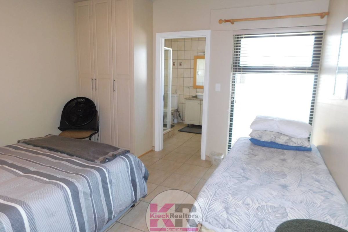 A bedroom featuring built-in cupboards and an en-suite bathroom with tiled flooring throughout.