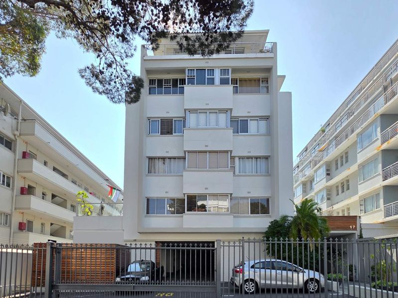 Front elevation of a multi-story apartment building featuring a secure gated entrance and multiple levels of residential units with balconies.