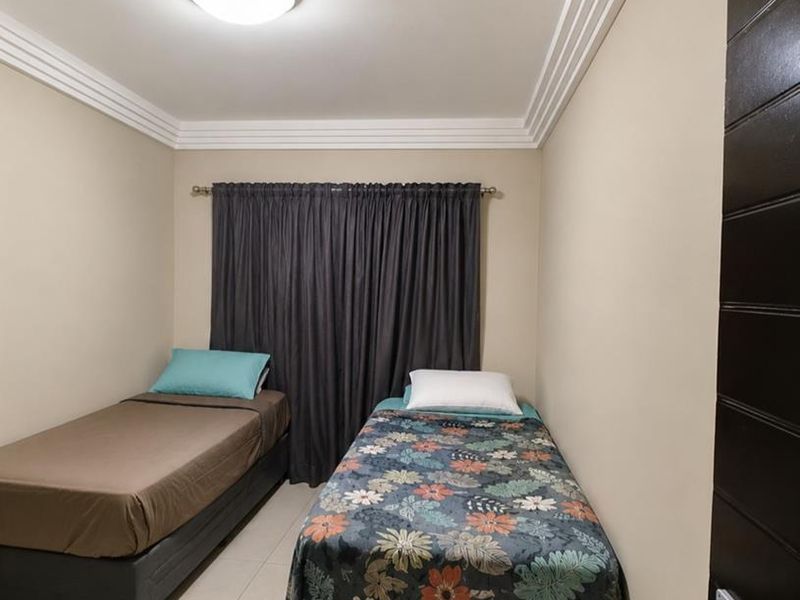 A well-maintained bedroom featuring neutral wall tones, tiled flooring, decorative ceiling cornicing, and a flush mount light fixture.