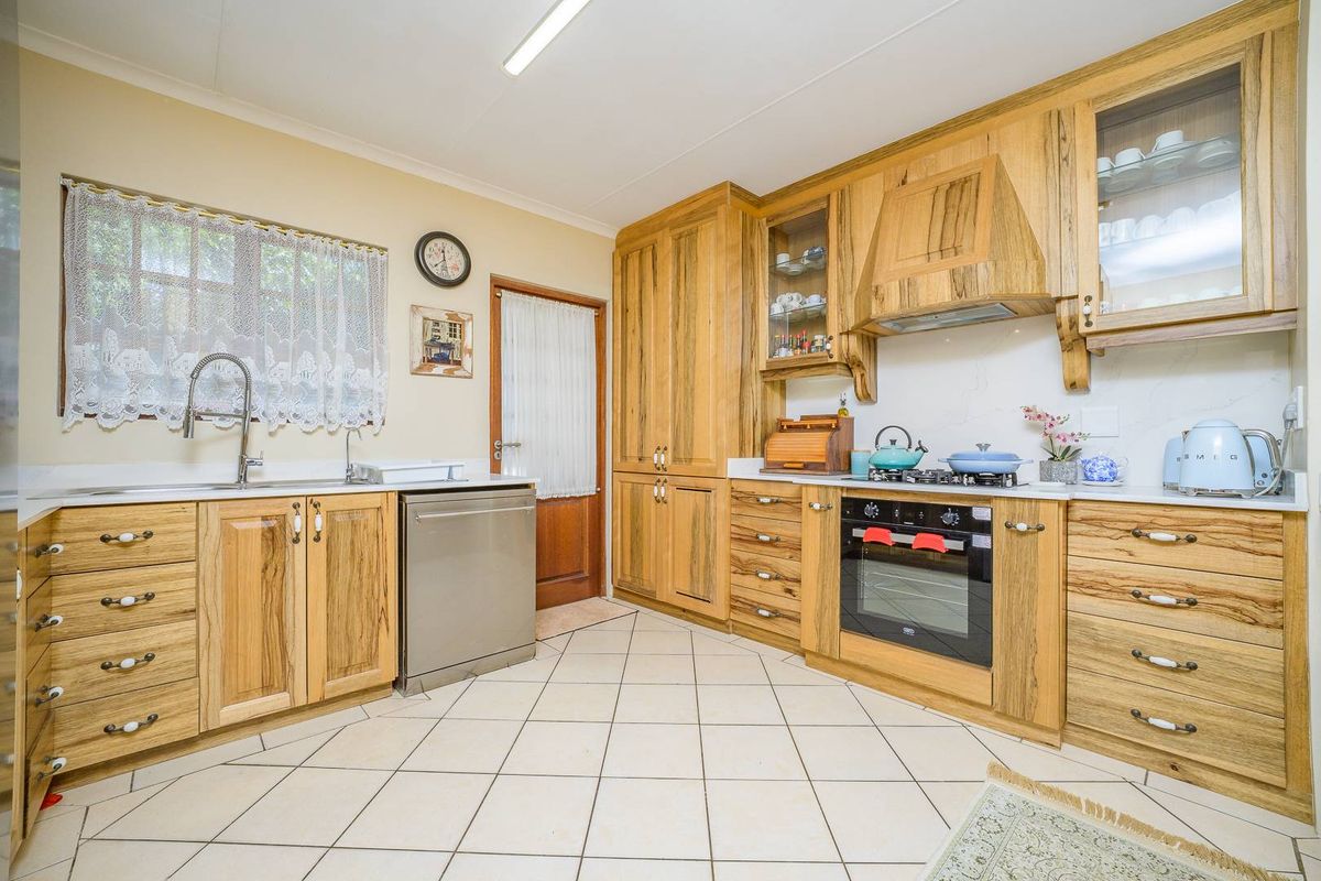 A functional kitchen featuring solid wood cabinetry, built-in oven, gas hob, extractor fan, and tiled flooring with ample counter space.