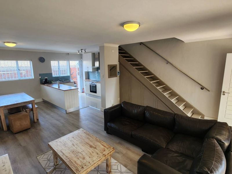 Open-plan living and dining area featuring a modern kitchen with built-in appliances and a staircase leading to the upper level.