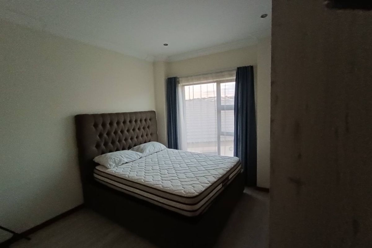 A bedroom featuring recessed ceiling lighting and a large window with curtains, providing natural light to the space.