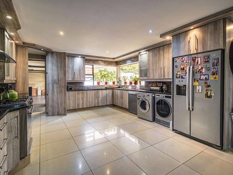Spacious kitchen featuring modern wood-look cabinetry, granite countertops, integrated appliances, and tiled flooring with ample natural light.