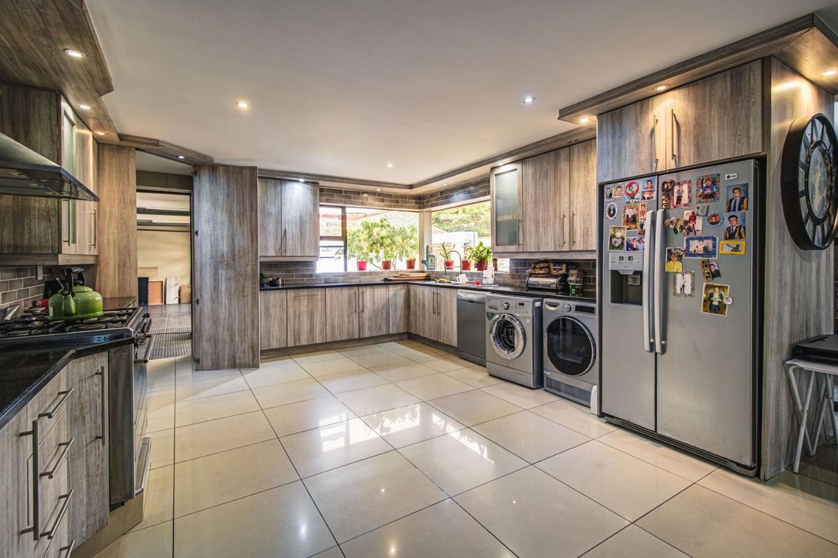 Spacious kitchen featuring modern wood-look cabinetry, granite countertops, integrated appliances, and tiled flooring with ample natural light.