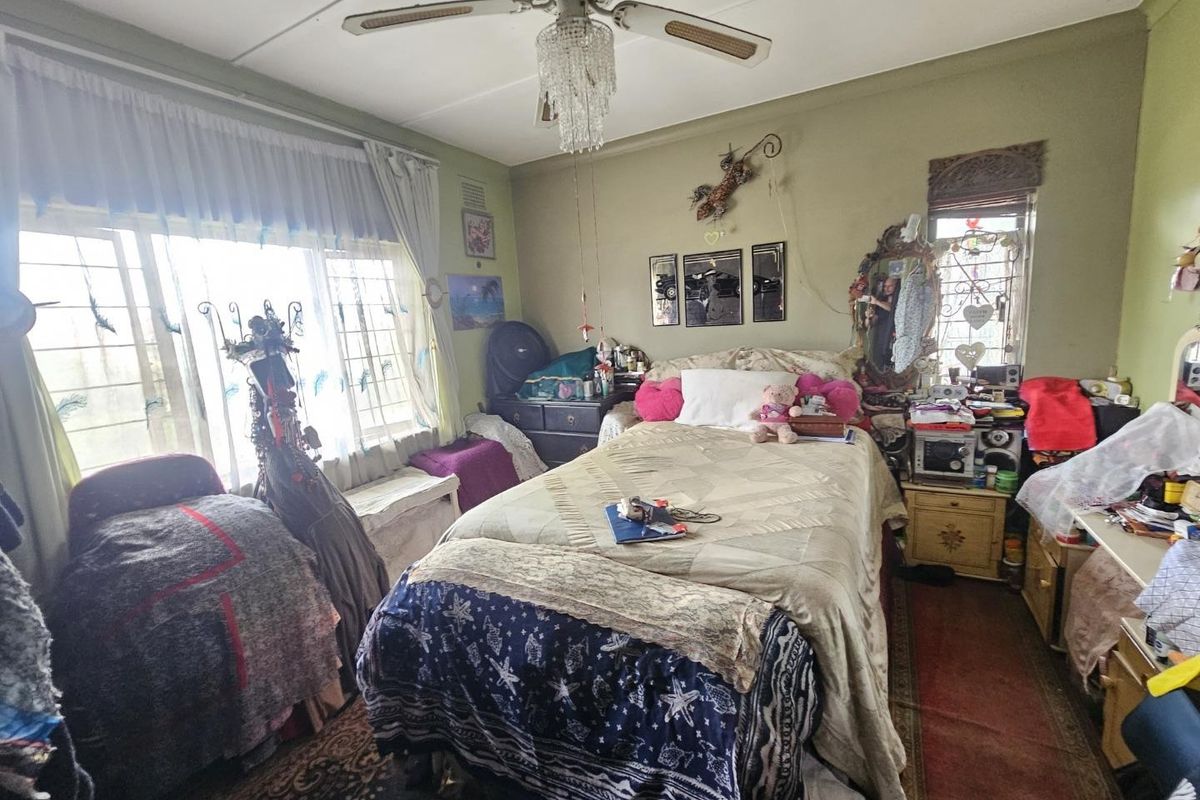 A bedroom featuring a ceiling fan and security bars on the windows, requiring cosmetic updates to improve the overall condition and appeal.